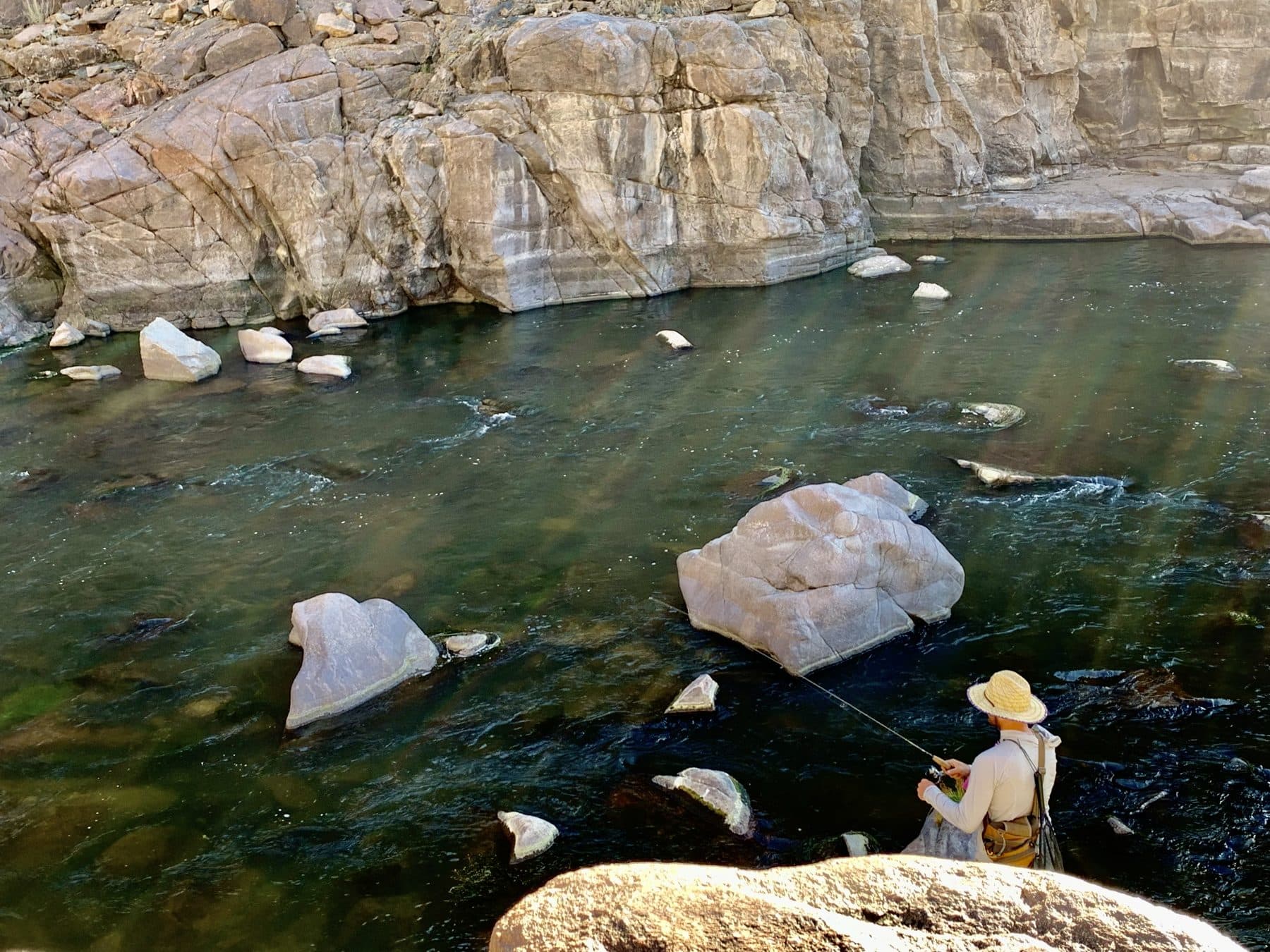 A fly fisherman working a deep canyon pool