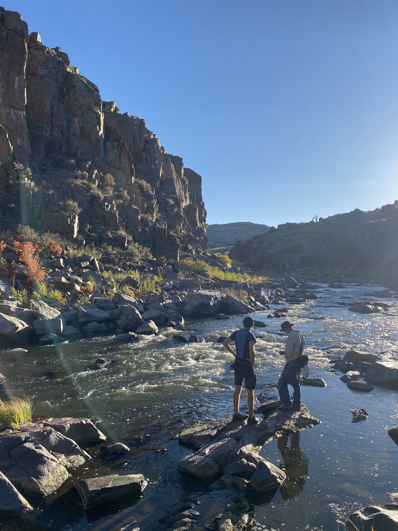 Anglers scouting a canyon river in late-day light