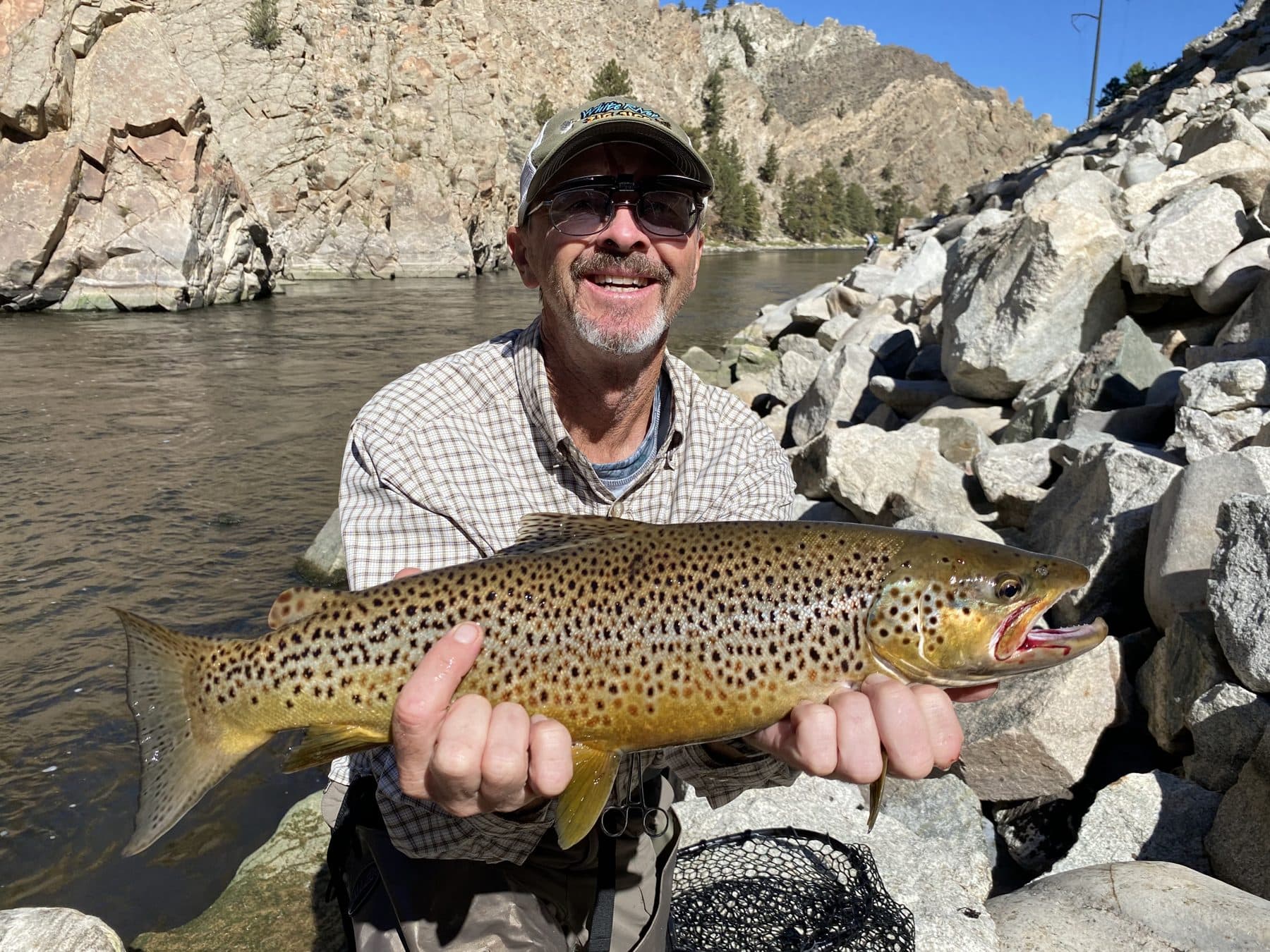 An angler smiling with a large brown trout